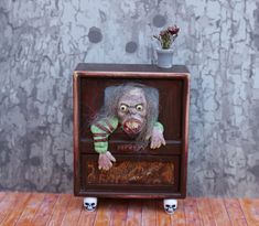 a creepy doll is sitting on top of an old tv