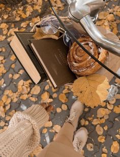 a person standing next to a bike with a book and some leaves on the ground