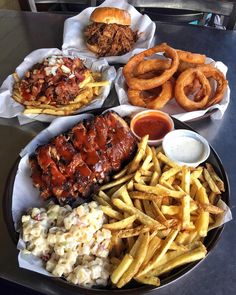 barbecue ribs, french fries, coleslaw and onion rings on a table