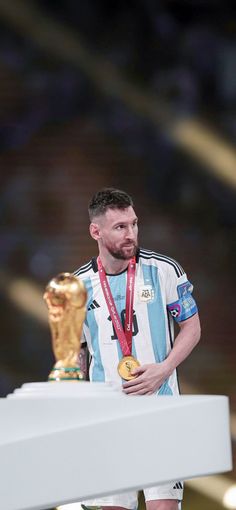 a man standing next to a trophy on top of a white table