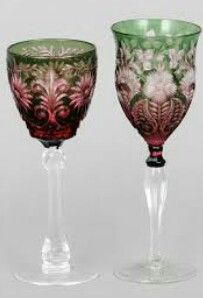 two glass goblets sitting next to each other on a white surface with flowers painted on them