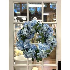 a blue wreath is hanging on the window sill in front of a coffee cup