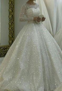 a woman in a white wedding dress standing next to a mirror