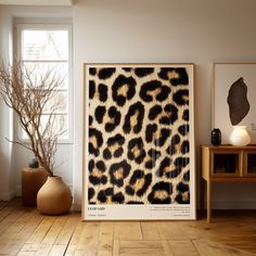 an animal print is on the wall next to a table and vase with a plant in it