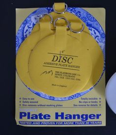 a yellow and blue plate hanger sitting on top of a black table next to a white disc