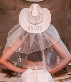 the back of a woman's head wearing a veil and bridal hat that says bride