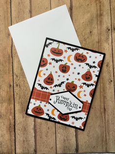 a card with pumpkins and bats on it, sitting on top of a wooden table