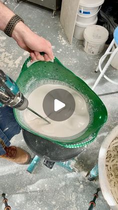 a person is using a machine to make a bowl with something white and green in it