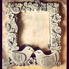 an intricately carved wooden frame with two birds in the middle and flowers around it