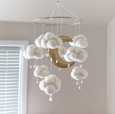 a baby crib mobile with white fluffy balls hanging from it's sides and the moon in the middle