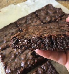 a person holding up a chocolate brownie in their hand