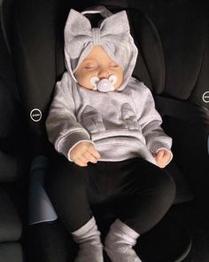 a baby sleeping in a car seat wearing a cat costume