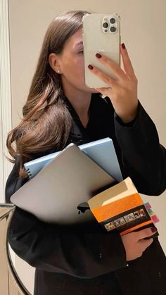 a woman taking a selfie with her cell phone and many folders in front of her