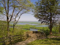 the path to the top of the hill is next to some trees and water in the distance