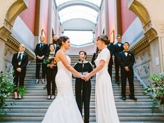 the bride and groom are holding hands on the stairs at their wedding ceremony in front of other guests