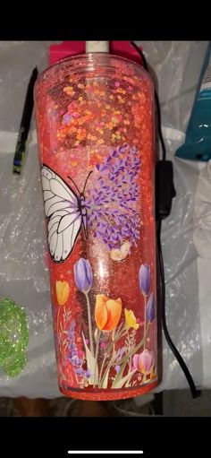 a bottle with flowers and a butterfly painted on it