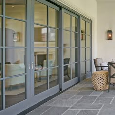 an outdoor patio with chairs and tables next to glass doors that lead into the living room