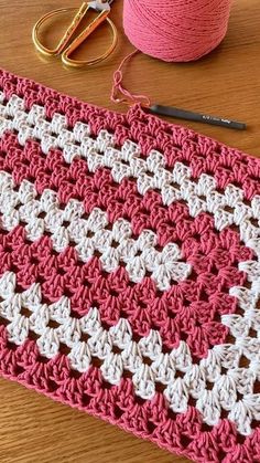 crocheted pink and white afghan next to scissors and yarn