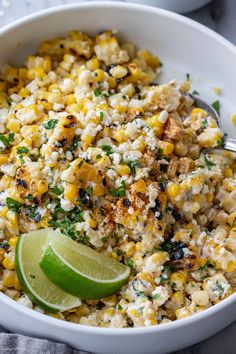 a white bowl filled with corn and topped with a lime