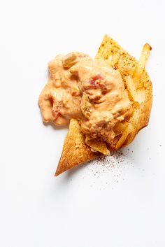 a piece of bread with some kind of sauce on it and chips in the foreground