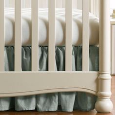 there is a white crib with blue and green bedding on the bottom rail