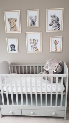 a baby's crib with pictures on the wall above it and stuffed animals