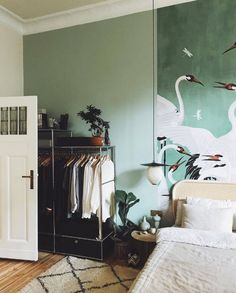 a room with a bed, closet and painting on the wall in it's corner