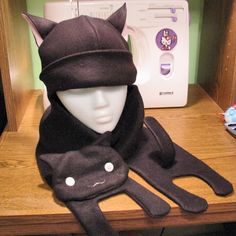 a black cat hat and scarf on a table next to a sewing machine with buttons