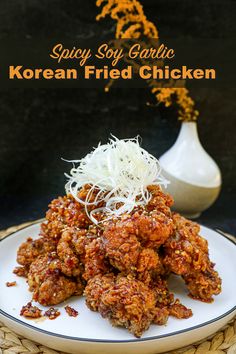 korean fried chicken on a white plate with sprouts and shredded parmesan