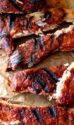 barbecue ribs with bbq sauce sitting on top of a piece of waxed paper