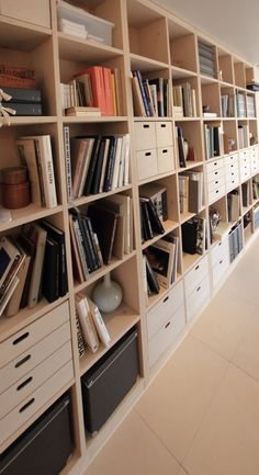 a bookshelf filled with lots of books on top of white drawers in a room