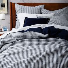 a bed with blue and white striped comforter in a bedroom next to a night stand