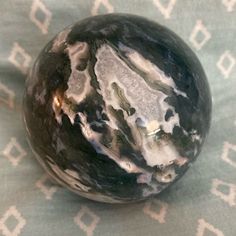 a black marble ball sitting on top of a blue and white tablecloth covered floor