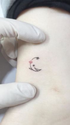 a person with a tattoo on their arm holding up a small moon and crescent symbol