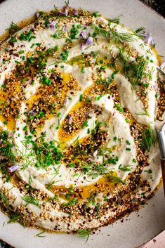 a white plate topped with hummus and herbs