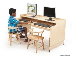 a young boy sitting in front of a computer desk with a monitor and keyboard on it