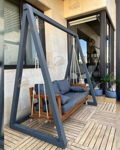 a swing chair sitting on top of a wooden floor next to a building with glass doors