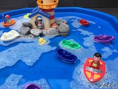 there is a play table with toys in the water and on top of it are boats