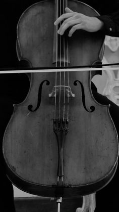 a black and white photo of someone playing the cello