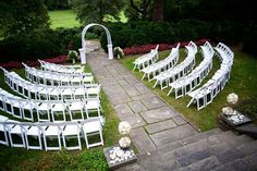 an outdoor ceremony setup with white chairs and flowers