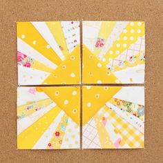 four pieces of yellow and white paper on a cork board