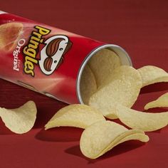 an open can of potato chips on a red surface with two pieces cut out to show the inside