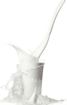 a glass full of milk with a spoon sticking out of the top, on a white background