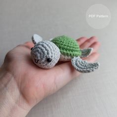 a small crocheted turtle sitting on top of someone's hand