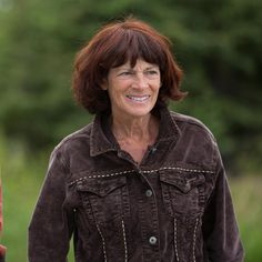 a woman holding an umbrella and smiling at the camera