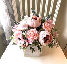 a vase filled with pink flowers sitting on top of a white table next to a window