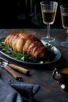 croissants and greens on a plate with two glasses of wine in the background