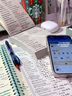 a cell phone sitting on top of an open notebook next to a pen and paper