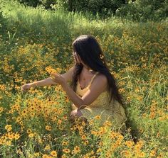 a woman sitting in a field of yellow flowers