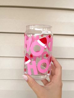 a person holding up a glass with the word boo hoo on it in pink and red